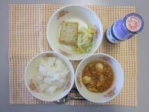テーブルクロスに並べられたごはん・牛乳・とり肉とやさいのケチャップ炒め煮・さかなのすりみ焼き・コーンサラダの写真
