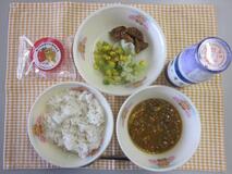 テーブルクロスに並べられた麦ごはん・牛乳・いなりキーマカレー・青じそポテト・グリーンアスパラガスのサラダ・いちごあんの水まんじゅうの写真