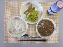 テーブルクロスに並べられた麦ごはん・牛乳・米粉のハヤシライス・めひかりフライ・カラフルソテーの写真