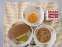 テーブルクロスに並べられたミルクロールパン・牛乳・トマトスープ・かぼちゃグラタン・冷凍みかんの写真