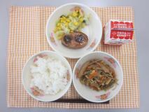 テーブルクロスに並べられたごはん・牛乳・五目きんぴら・ハンバーグの青じそソースかけ・やさい炒めの写真