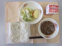 テーブルクロスに並べられたソフトめん・牛乳・ミートソース・ポテトサラダ・りんごの写真