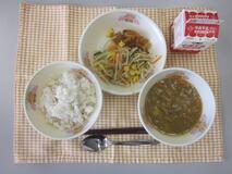 テーブルクロスに並べられた麦ごはん・牛乳・米粉のカレーライス・ごぼうサラダ・福神漬の写真