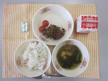 テーブルクロスに並べられた麦ごはん・牛乳・わかめスープ・ビビンバ・ミニトマト・角チーズの写真