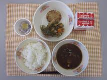 テーブルクロスに並べられたごはん・牛乳・ぶた汁・キャベツ入りつくね・糸切りこんぶの煮付け・なっとうの写真