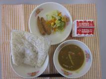 テーブルクロスに並べられたソフトめん・牛乳・米粉のカレーソース・めひかりフライ・フレンチサラダの写真