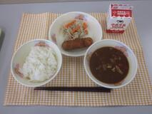 テーブルクロスに並べられたごはん・牛乳・みそしる・いかフライのレモン煮・もやし炒めの写真