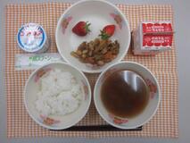 テーブルクロスに並べられたごはん・牛乳・いなか汁・しそ風味のさっぱりぶた大豆・いちご・ヨーグルトの写真