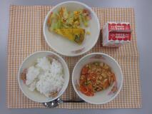 テーブルクロスに並べられたごはん・牛乳・とり肉とやさいのケチャップ炒め煮・スパニッシュオムレツ・フレンチサラダの写真