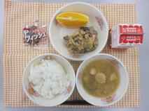 テーブルクロスに並べられたごはん・牛乳・中華スープ・ぶた肉のかき油炒め・ネーブルオレンジ・アーモンド小魚の写真
