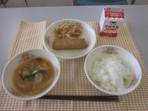 テーブルクロスに並べられたごはん・牛乳・中華スープ・はるまき・もやしのあま酢あえの写真
