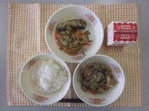 テーブルクロスに並べられたごはん・牛乳・いりどり・いわしのうめ煮・くきわかめの煮付けの写真