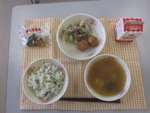 テーブルクロスに並べられたわかめごはん・牛乳・すまし汁・ごぼう入りつくね・赤しそあえ・かしわもちの写真