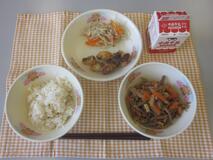 テーブルクロスに並べられた玄米ごはん・牛乳・細切りやさいの炒め煮・たこから揚げ・もやし炒めの写真