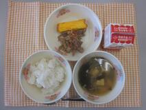 テーブルクロスに並べられたごはん・牛乳・わかめスープ・厚焼きたまご・ピリ辛丼の写真