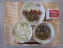 テーブルクロスに並べられたごはん・牛乳・つくね汁・大豆と小魚のごまがらめ・ミニトマトの写真