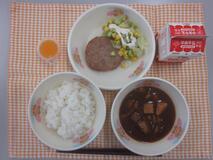テーブルクロスに並べられたごはん・牛乳・えいようゴロゴロ！パワーみそしる・れんこんハンバーグ・グリーンアスパラガスのサラダ・ミニゼリー（蒲郡みかん）の写真