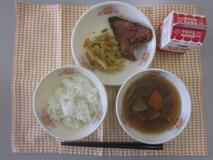 テーブルクロスに並べられたごはん・牛乳・五目汁・ぶりの竜田揚げ・じゃがいものきんぴらの写真