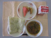 テーブルクロスに並べられた中華めん・牛乳・五目ラーメン・ぎょうざ・すいかの写真