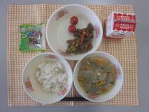 テーブルクロスに並べられた麦ごはん・牛乳・はるさめスープ・ビビンバ・ミニトマト・かんそう小魚の写真