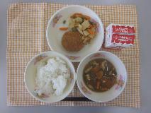 テーブルクロスに並べられたごはん・牛乳・とうがんのみそ汁・えだ豆コロッケ・たけのこのピリ辛炒めの写真