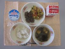 テーブルクロスに並べられた麦ごはん・牛乳・わかめスープ・ビビンバ（肉）・ビビンバ（やさい）・フローズンヨーグルトの写真