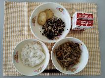 テーブルクロスに並べられたごはん・牛乳・細切りやさいの炒め煮・もち麦入りはんぺん・ひじきと大豆の煮付けの写真