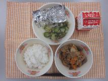 テーブルクロスに並べられたごはん・牛乳・いりどり・さけの銀紙焼き・きゅうりの塩こんぶあえの写真