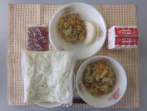 テーブルクロスに並べられた冷やし白玉うどん・牛乳・ぶた肉とやさいの炒め煮・かき揚げ・なし・うどんつゆの写真