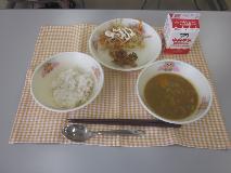 テーブルクロスに並べられた麦ごはん・牛乳・米粉のチキンカレーライス・ごぼうサラダ・福神漬・マヨネーズドレッシングの写真