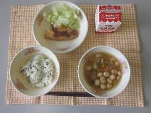 テーブルクロスに並べられたわかめごはん・牛乳・ふ玉汁・あじフライ・ボイルキャベツ・パックソースの写真