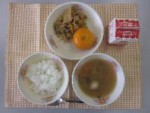 テーブルクロスに並べられたごはん・牛乳・うずらたまごスープ・ぶたキムチ丼・冷凍みかんの写真