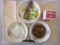 テーブルクロスに並べられたごはん・牛乳・五目汁・いわしのかば焼き丼・しんこあえの写真