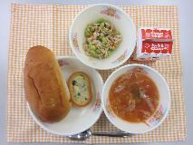 テーブルクロスに並べられたレーズンロールパン・牛乳・ミネストローネ・やさいグラタン・ツナとえだ豆のソテーの写真