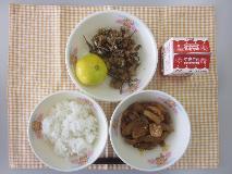 テーブルクロスに並べられたごはん・牛乳・煮みそ・大豆と小魚のごまがらめ・みかんの写真