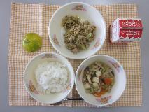 テーブルクロスに並べられたごはん・牛乳・とうふの中華スープ煮・青じそ入りガパオライス・みかんの写真