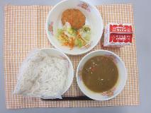 テーブルクロスに並べられたソフトめん・牛乳・米粉のカレーソース・えびカツ・フレンチサラダ・フレンチドレッシングの写真
