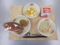 テーブルクロスに並べられた愛知の米粉入りパン・牛乳・かぶの豆乳クリーム煮・メンチカツ・フルーツポンチ・白玉だんごの写真
