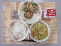 テーブルクロスに並べられたごはん・牛乳・かきたま汁・キャベツ入りつくね・ごぼうサラダ・ココア糖・ごまドレッシングの写真