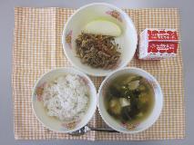テーブルクロスに並べられた麦ごはん・牛乳・わかめスープ・いなりビビンバ・りんごの写真