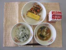 テーブルクロスに並べられたわかめごはん・牛乳・白玉ぞう煮・厚焼きたまご・れんこん炒めの写真