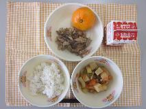 テーブルクロスに並べられた麦ごはん・牛乳・やさいのふくめ煮・ぶた肉丼・みかんの写真