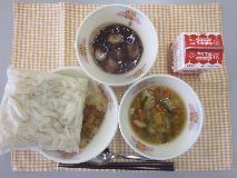 テーブルクロスに並べられたきしめん・牛乳・五目きしめん・にぎすのフライ・ミニぜんざい・パックソースの写真