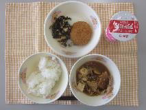 テーブルクロスに並べられたごはん・はっこう乳・ぶた汁・キャベツ入りメンチカツ・ひじきと大豆の煮付けの写真