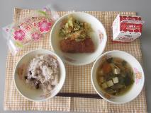 テーブルクロスに並べられた赤はん・牛乳・すまし汁・いかフライのレモン煮・ごまあえ・米粉のいちごクレープの写真