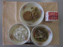テーブルクロスに並べられた麦ごはん・牛乳・沢煮わん・和風コロッケ・ツナそぼろ丼の写真