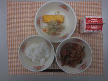 テーブルクロスに並べられたごはん・牛乳・生揚げのみそ煮・厚焼きたまご・三色炒めの写真