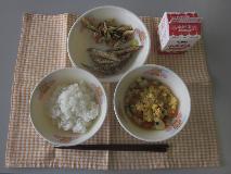 テーブルクロスに並べられたごはん・牛乳・親子煮・きびなごのから揚げ・こまつなと油揚げのごま炒めの写真