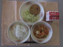 テーブルクロスに並べられたごはん・牛乳・とり肉とやさいのケチャップ炒め煮・コーンはんぺん・キャベツ炒めの写真