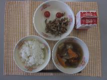 テーブルクロスに並べられたごはん・牛乳・つくね汁・大豆と小魚のごまがらめ・ミニトマトの写真